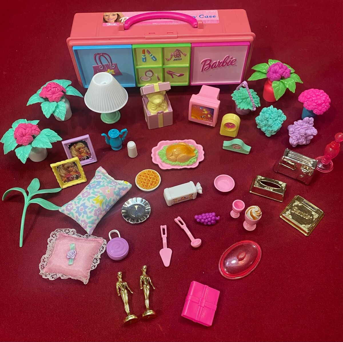 Barbie accessories from the 1990s, including a suitcase with beauty and fashion symbols, a couple floral pillows, potted flowers, a rotisserie chicken, grapes, bread, clocks, picture frames, etc.